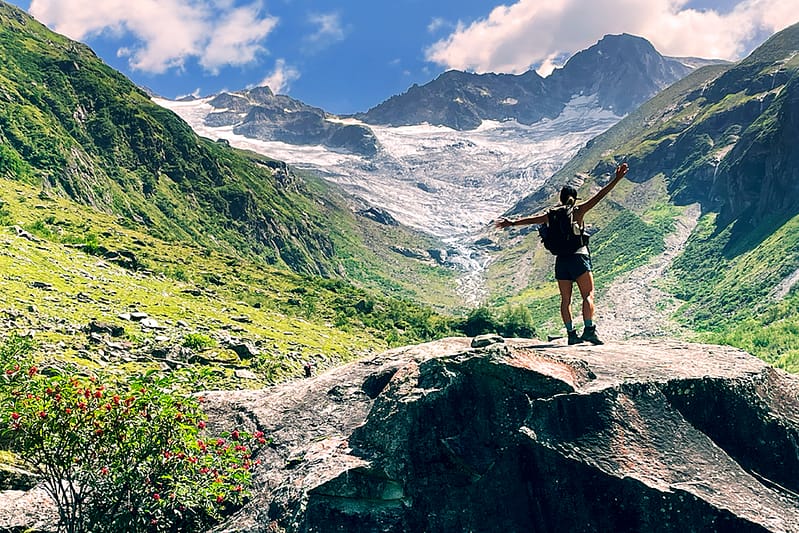 Über die Chakrenlehre Eine junge Frau steht auf einem Felsen in einem Alpen Hochtal und öffnet sich der schöpferischen Energie