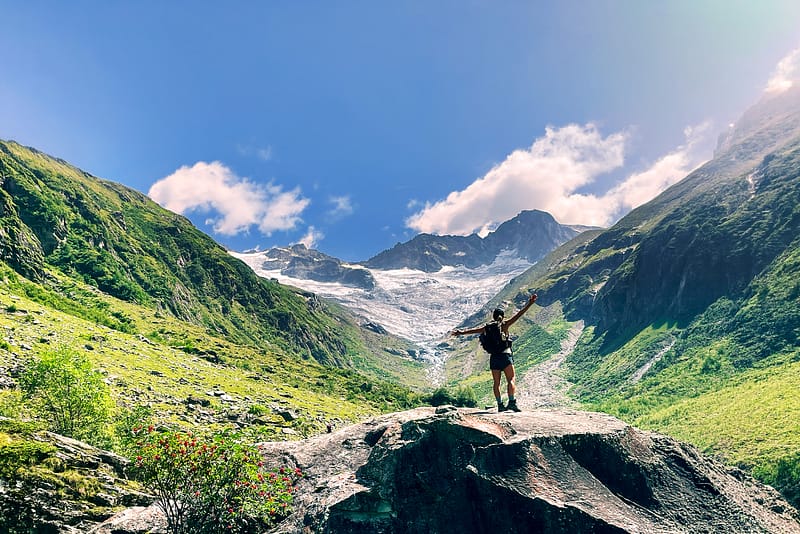 Über die Chakrenlehre Eine junge Frau steht auf einem Felsen in einem Alpen Hochtal und öffnet sich der schöpferischen Energie